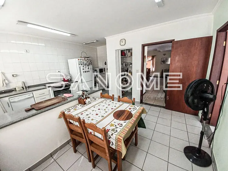 Cozinha com mesa de refeições e armários brancos