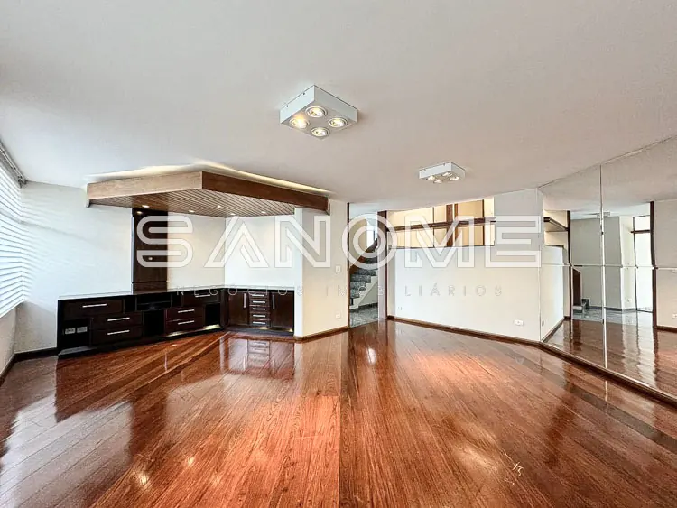 Sala ampla com piso de madeira e espelho