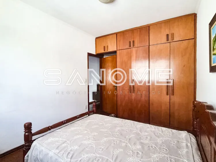 Quarto com cama de casal e guarda-roupa de madeira