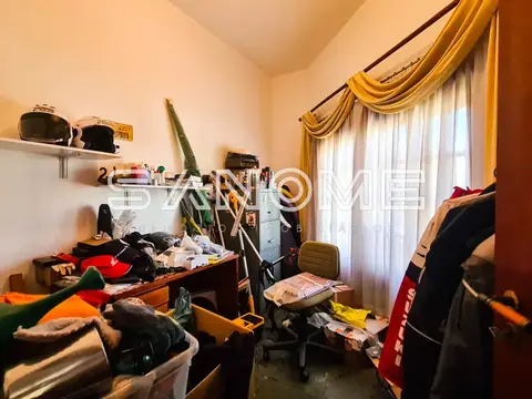 Quarto com roupas espalhadas e janela com cortina