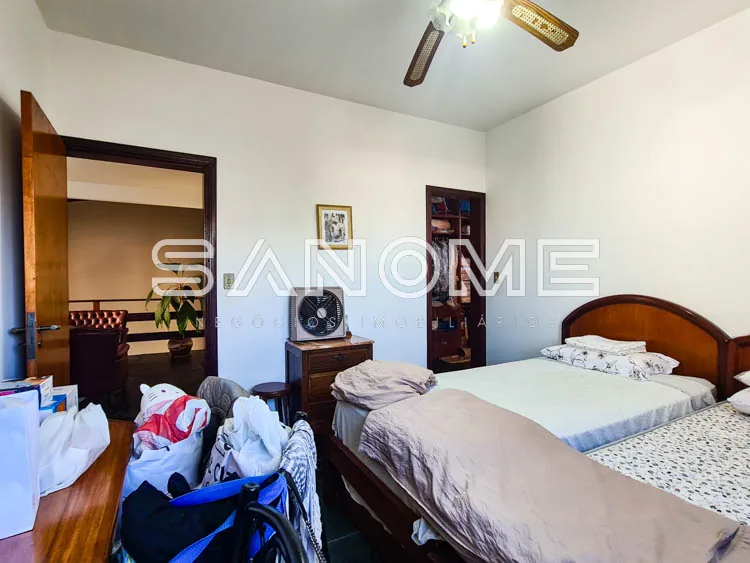 Quarto com cama de casal e roupas espalhadas