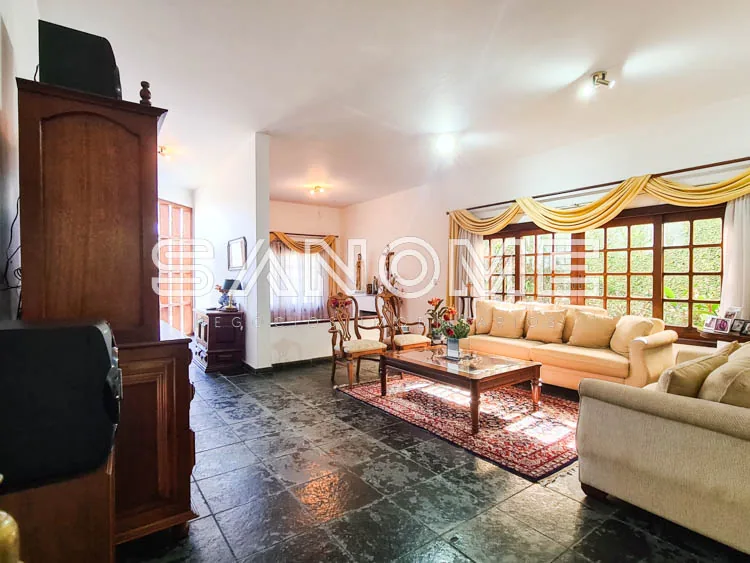 Sala de estar com sofás, janelões e cortinas douradas