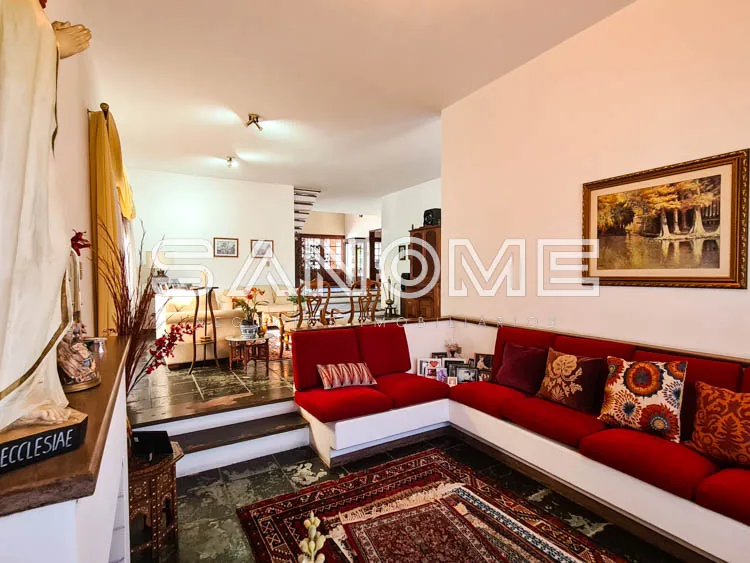 Sala de estar com sofá vermelho em L e tapete persa