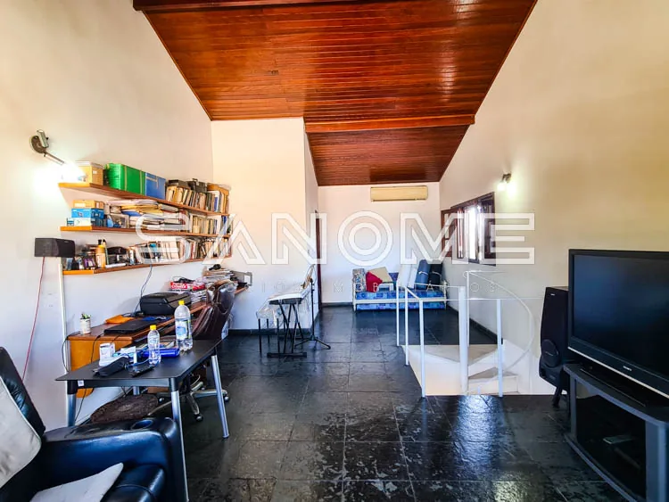 Sala com piso escuro, estantes de livros e TV