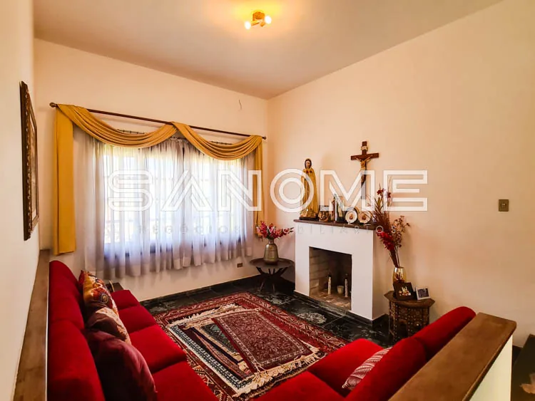 Sala com sofá vermelho, lareira e janela com cortinas douradas
