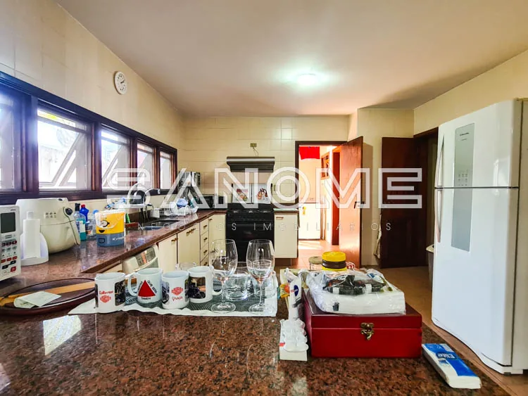 Cozinha ampla com bancada, geladeira e armários