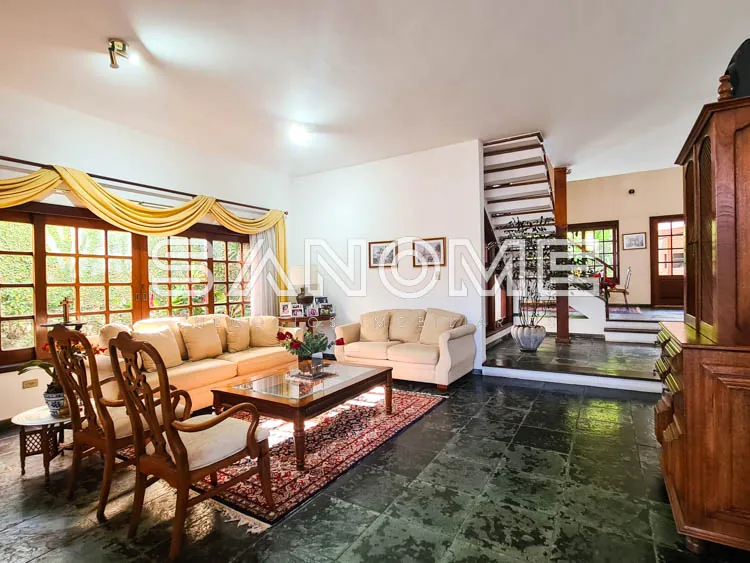 Sala de estar com sofá, poltronas e janelas amplas