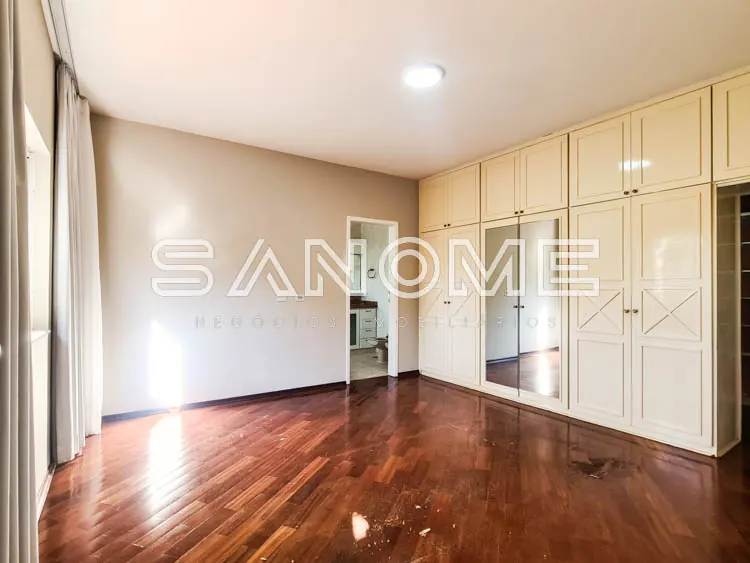 Quarto amplo com guarda-roupa espelhado e piso de madeira
