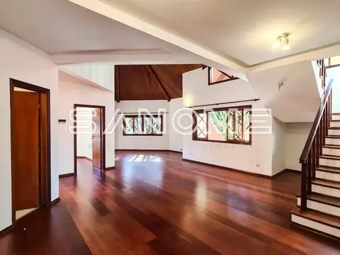 Sala ampla com piso de madeira e escada lateral