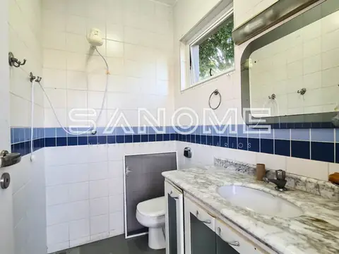 Banheiro com pia, vaso sanitário e azulejos brancos e azuis