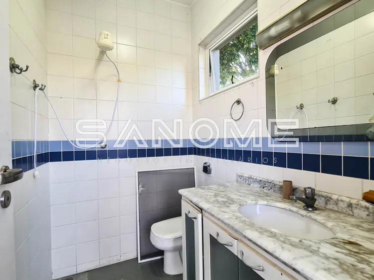 Banheiro com pia, vaso sanitário e azulejos brancos e azuis