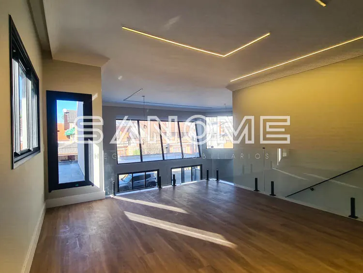 Sala ampla com piso de madeira e janelas panorâmicas