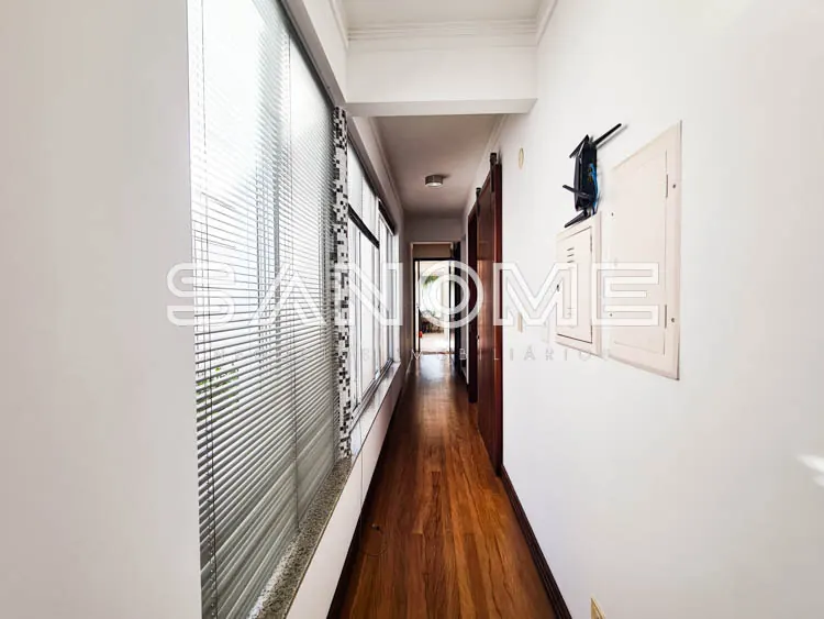 Corredor comprido com piso de madeira e janelas