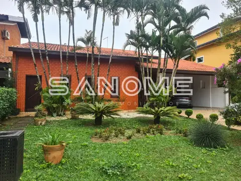 Fachada de casa com palmeiras e gramado frontal