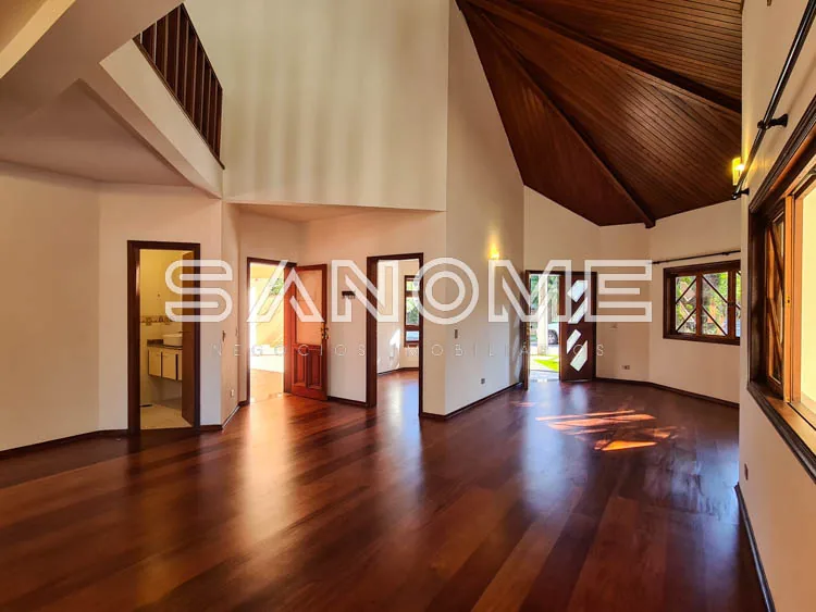 Sala ampla com piso de madeira e teto em meia água