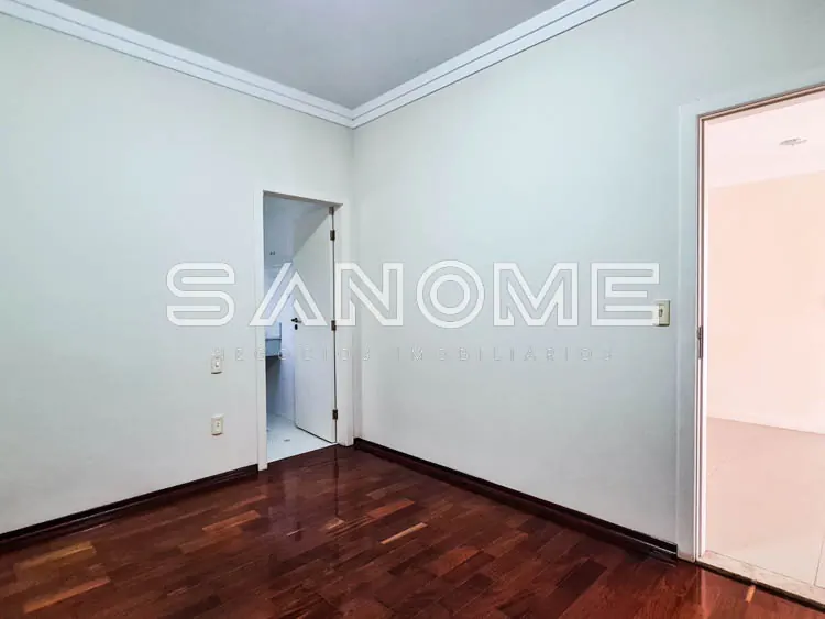 Quarto vazio com piso de madeira e portas brancas