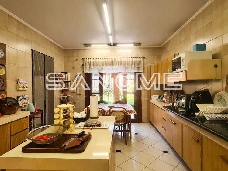 Cozinha com bancada, armários de madeira e acesso à sala