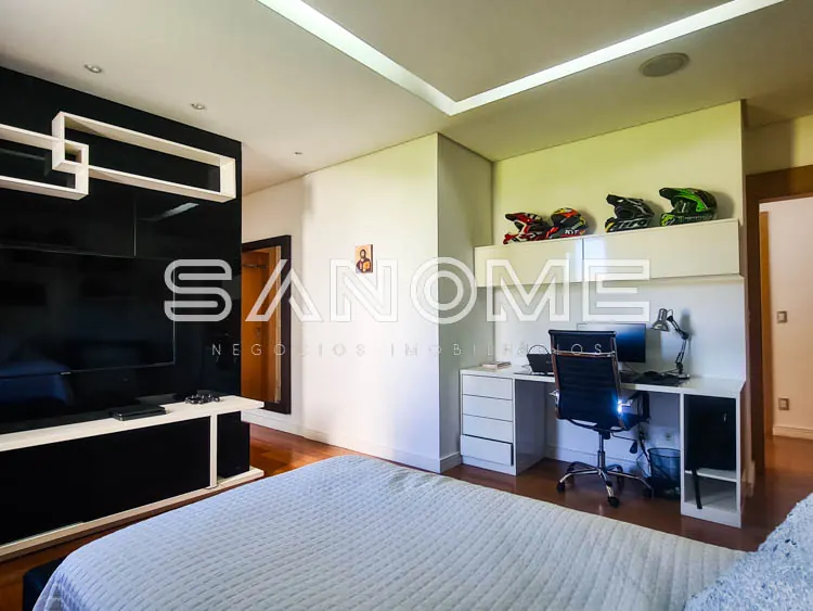 Quarto com cama de casal, painel de TV e escrivaninha