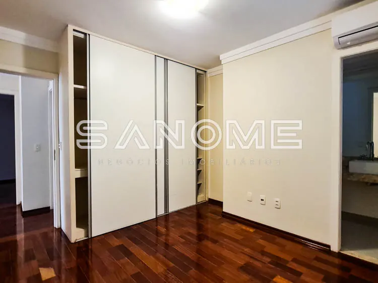Quarto com guarda-roupa espelhado e piso de madeira