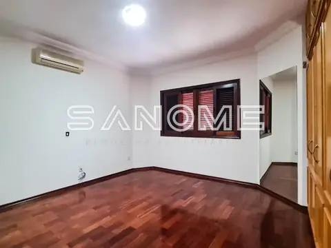 Sala vazia com piso de madeira e janela com veneziana