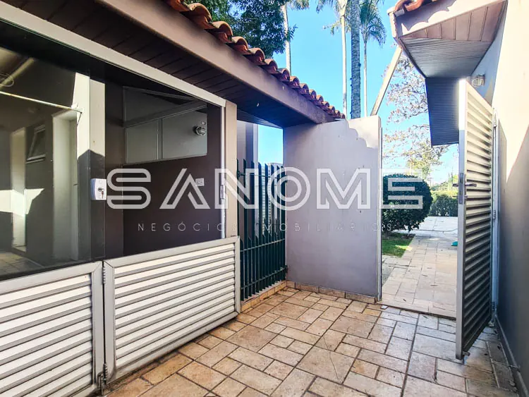 Entrada de casa com portão preto e parede cinza