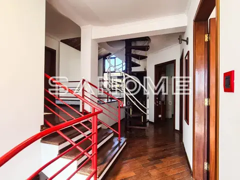 Corredor interno com escada de metal vermelho e porta de madeira