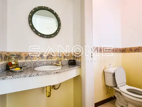 Banheiro com pia, espelho redondo e vaso sanitário