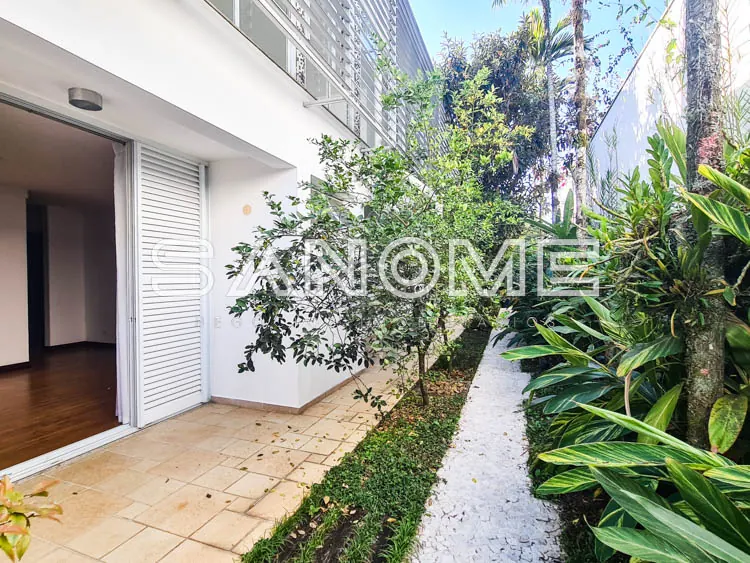 Área externa com porta de vidro e plantas verdes