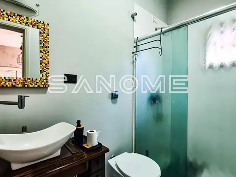 Banheiro com pia de louça e box com vidro fumê