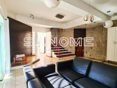 Sala de estar com sofá preto e escada ao fundo