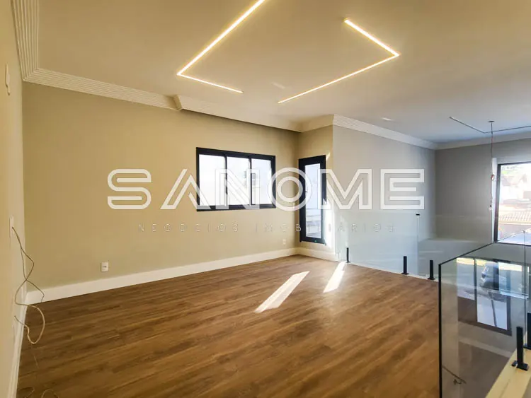 Sala ampla com piso de madeira e iluminação em sanca