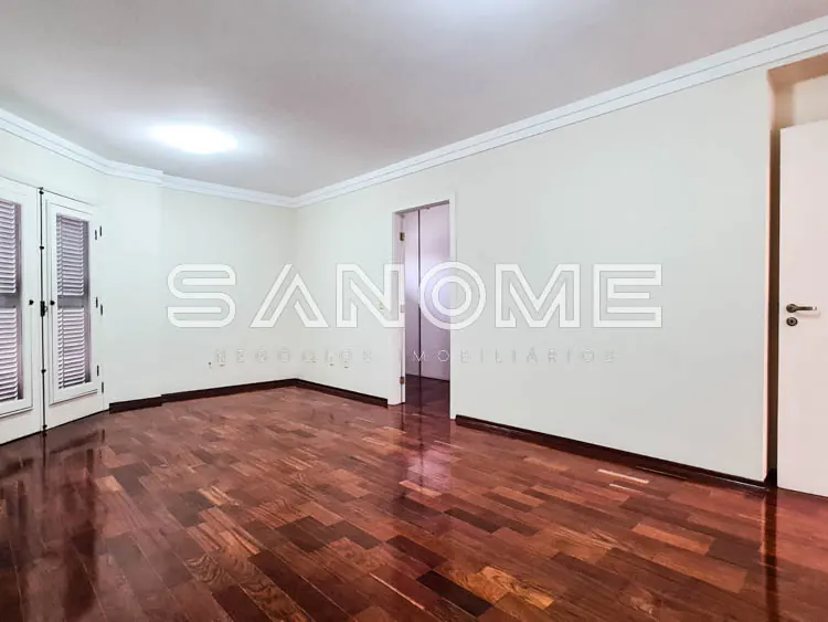Sala ampla com piso de madeira e portas brancas