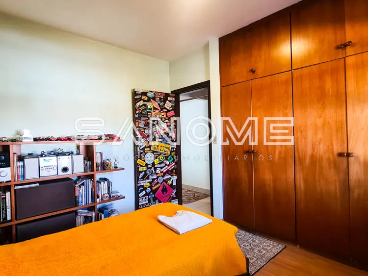 Quarto com cama laranja e guarda-roupa de madeira