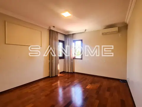 Sala ampla com piso de madeira e janelas com cortinas