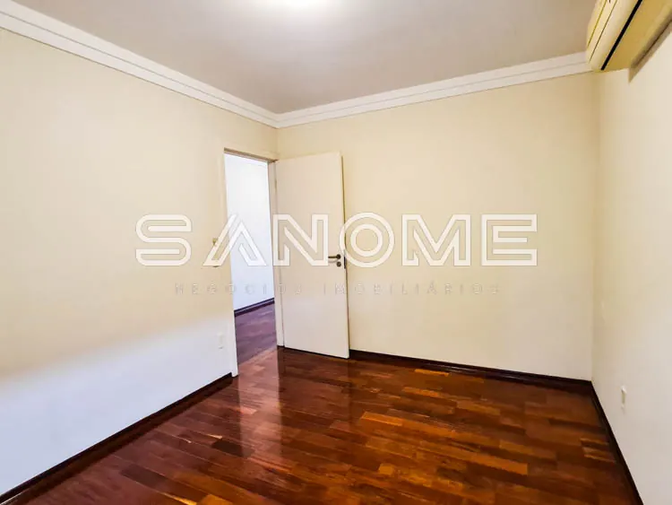 Quarto vazio com piso de madeira e parede amarela