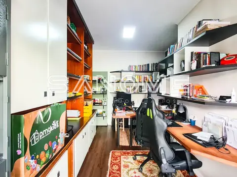 Escritório gamer com estantes, cadeira e dois monitores