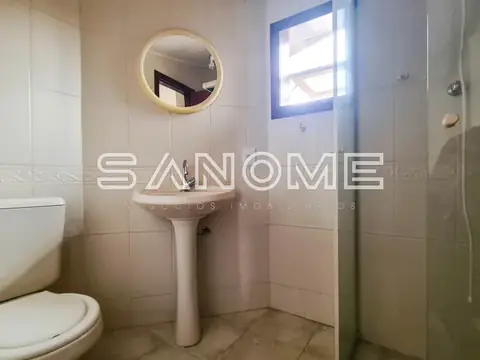 Banheiro com pia de pedestal e espelho iluminado