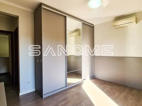Quarto com guarda-roupa espelhado e piso de madeira