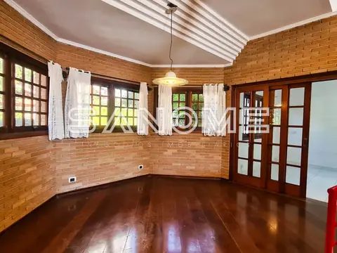 Sala ampla com paredes de tijolos, piso em madeira e janelas grandes