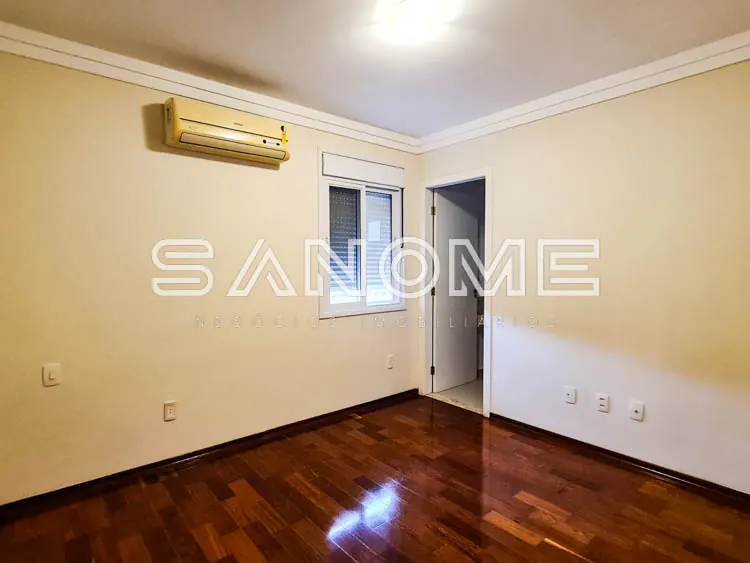 Sala vazia com piso de madeira e paredes bege