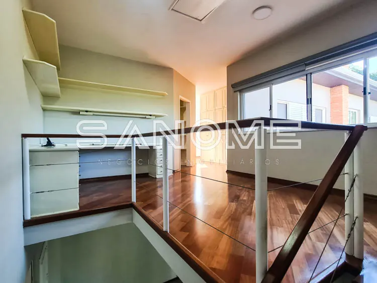 Sala com mezanino, piso de madeira e janelas amplas