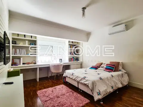 Quarto com cama, escrivaninha integrada e estantes brancas