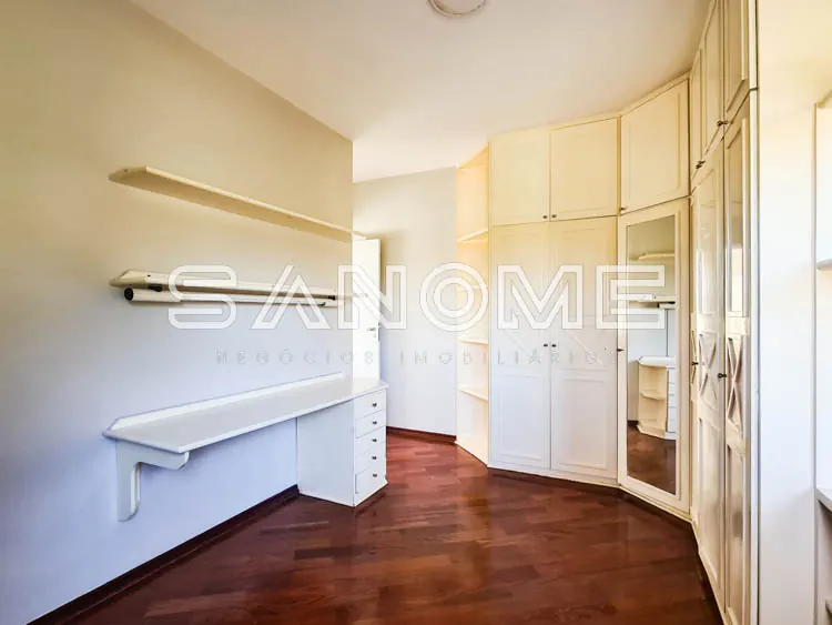 Closet com guarda-roupas brancos e piso de madeira
