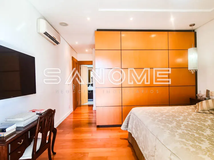 Quarto com cama, guarda-roupa laranja e piso em madeira