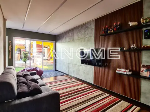 Sala de estar com sofá cinza e painel de madeira