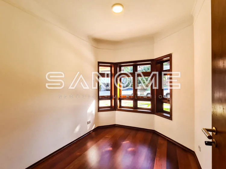 Sala com piso de madeira e janelas com vista externa