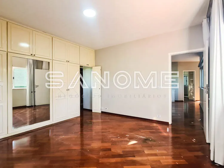 Quarto espaçoso com piso de madeira e guarda-roupa
