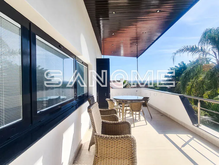 Varanda com móveis de vime e vista para área externa